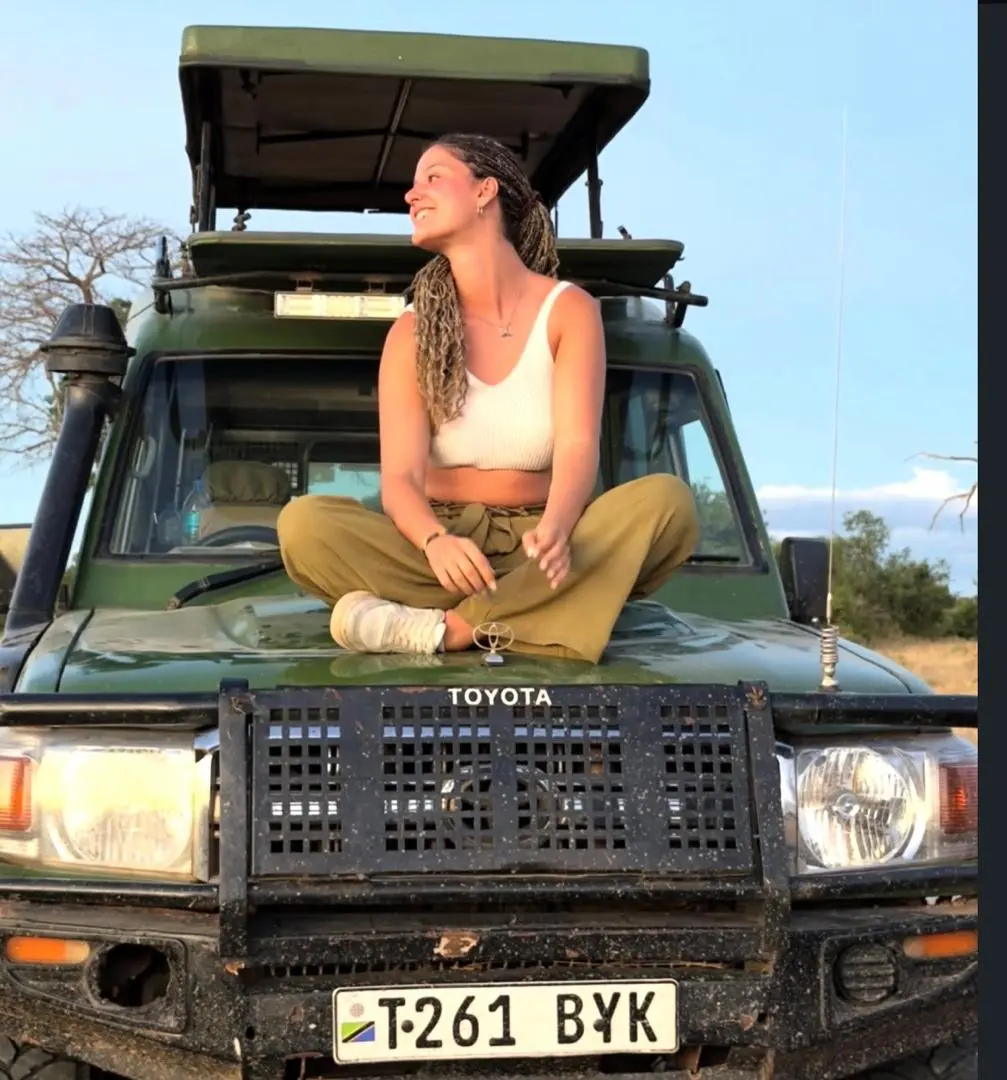Guest atop the safari vehicle at golden hour